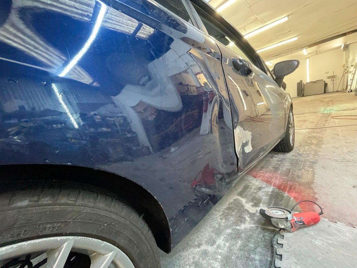Dark blue car with a dented and scratched rear door